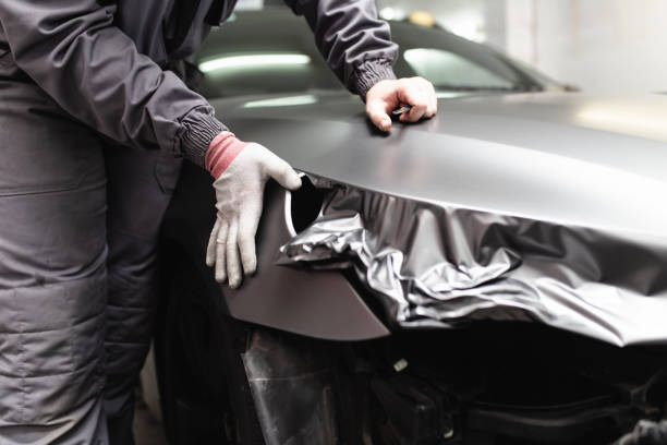 Car wrapping specialist putting vinyl foil or film on car. Selective focus.