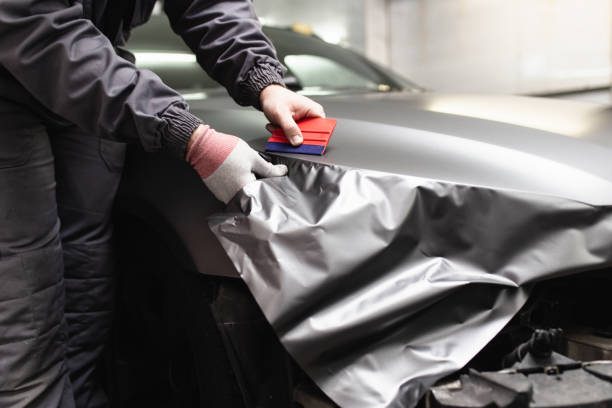 Car wrapping specialist putting vinyl foil or film on car. Selective focus.